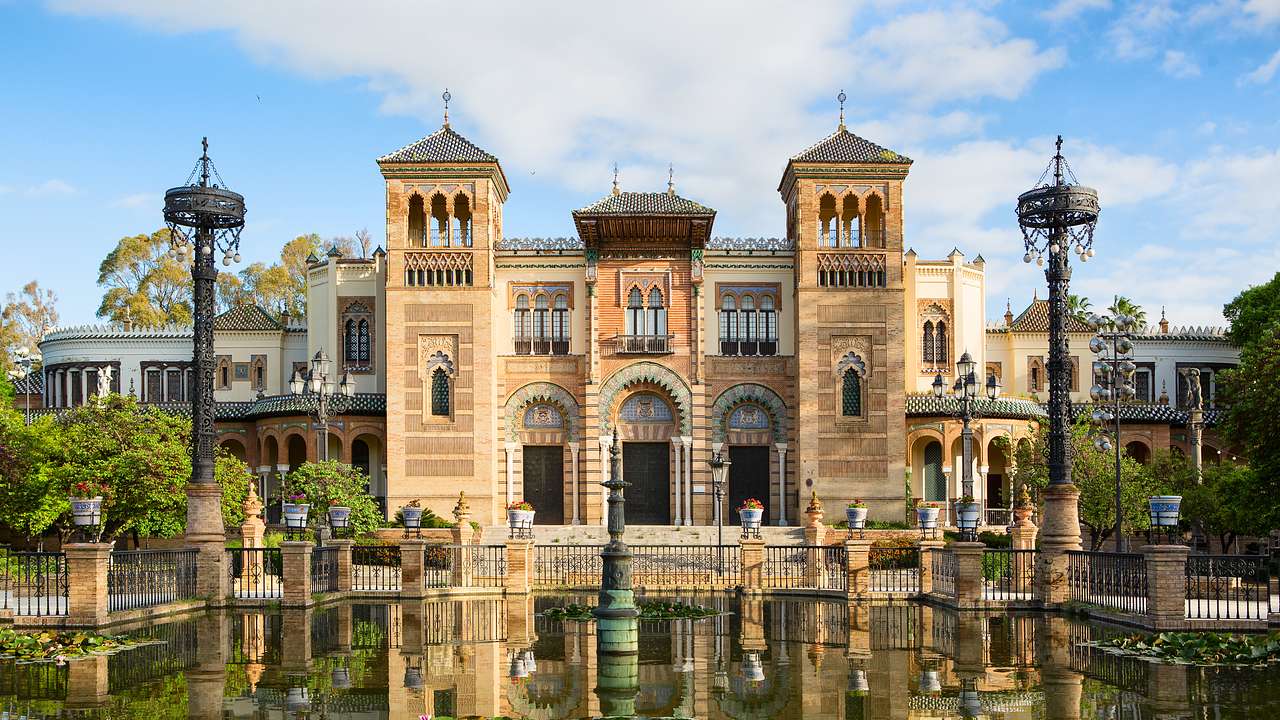 A Neo-Gothic-style building with two towers and a water garden in front