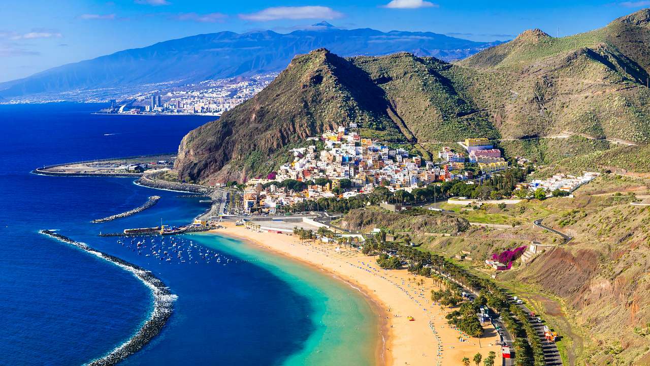 An aerial shot of mountains near a coastal city and clear waters