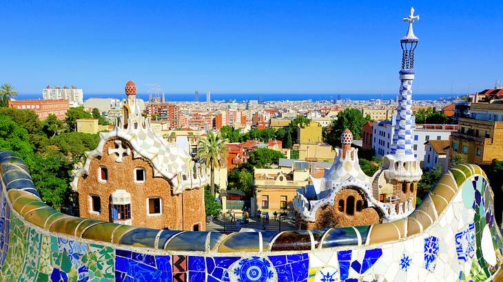 A short wall with colorful mosaic tiles and a view of a city