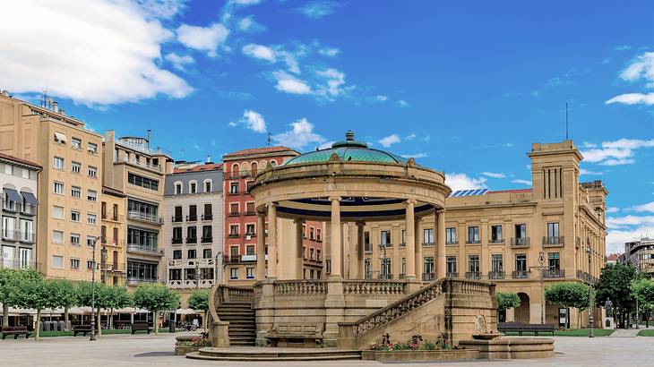 A gazebo in the middle of a paved open area surrounded by old buildings