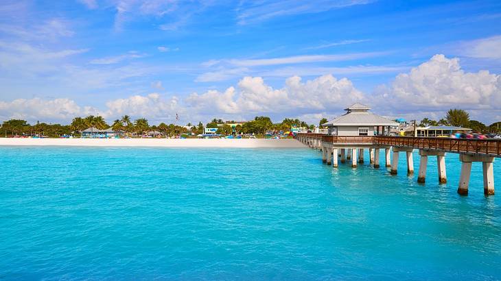 Turquoise ocean with a pier on one side and a sandy shore in the distance