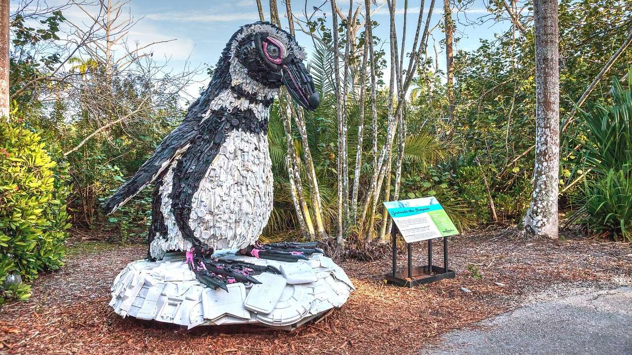 A penguin sculpture in a garden with trees