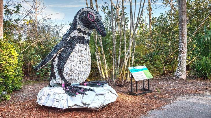 A penguin sculpture in a garden with trees