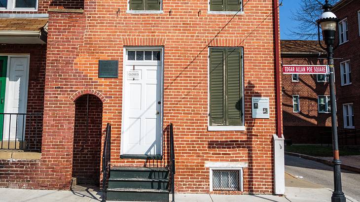 A brick house on the corner of a street near a lamppost