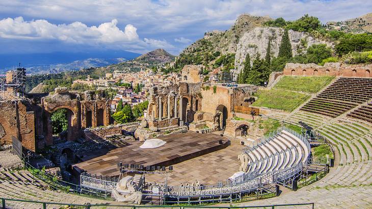 Panoramic view of the ruins of a theatre with seating facing a stage and columns