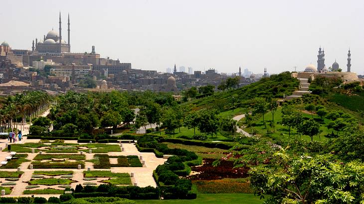 A beautiful view of a park's green landscape and flowers with a fortress behind it