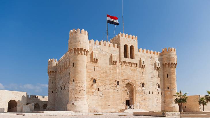 The medieval fort Citadel of Qaitbay with a flag on top on a bright sunny day The medieval fort Citadel of Qaitbay with a flag on top on a bright sunny day