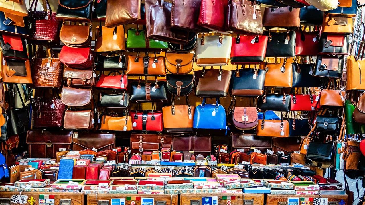 A display of leather handbags and wallets in various colors on a market stall
