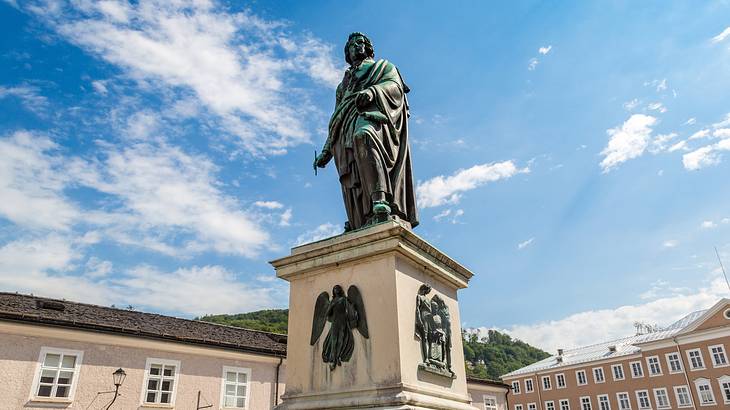 A low-angle view of a statue of a man on a pedestal surrounded by buildings