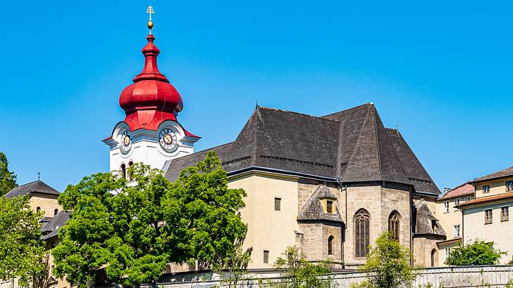 An old building with a spire with a red top near trees