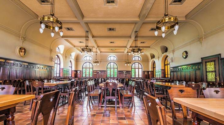 An interior of a restaurant with chandeliers and empty wooden tables and chairs