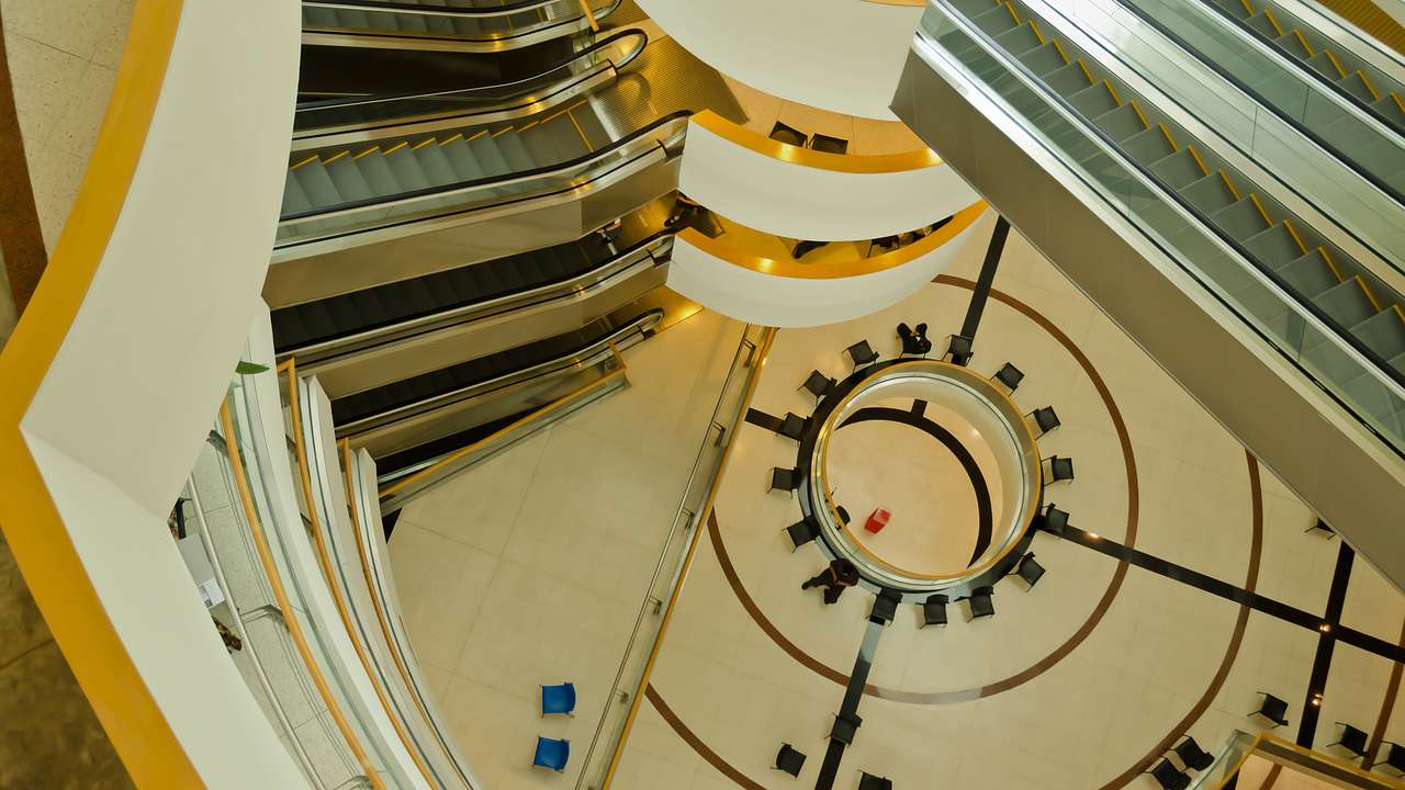 View of a building's winding hallways with escalators below from the top floor