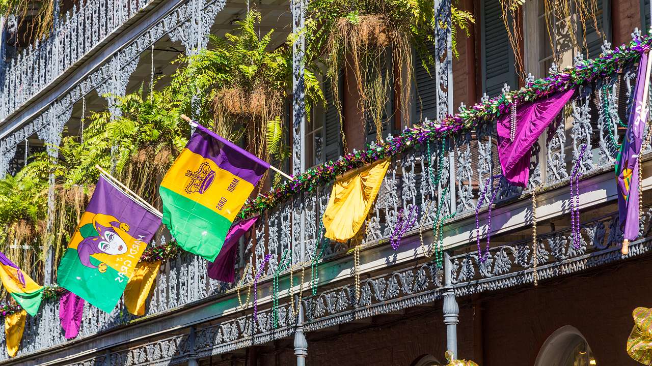 A balcony of a building with hanging plants and colorful flags