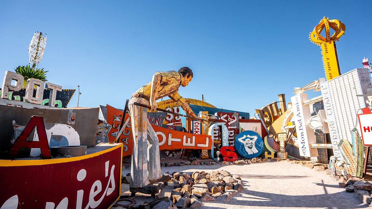 Old neon signs and sculptures displayed under a blue sky