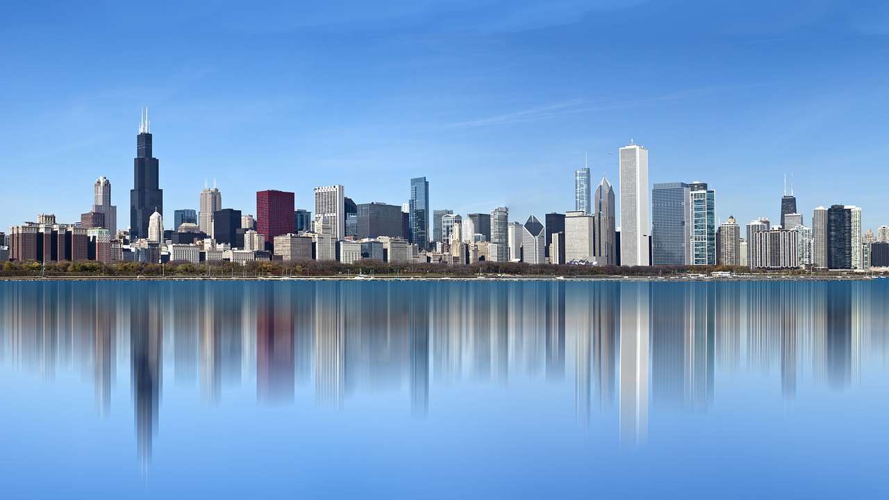 A city skyline filled with tall and short buildings, and a body of water in front