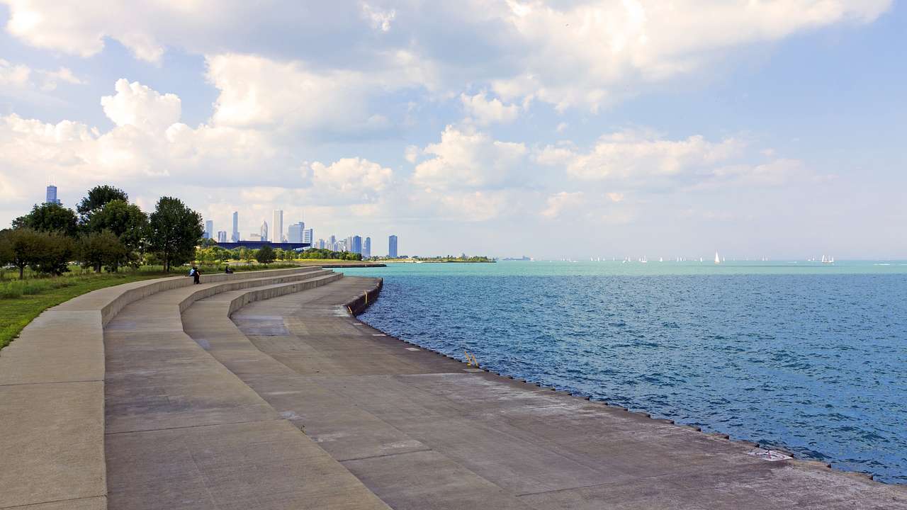 A park with concrete steps leading to a body of water, a city skyline in the distance