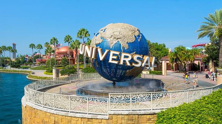 A large structure of a globe with a sign saying "Universal" near a body of water