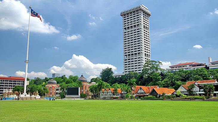 A wide green lawn with a flagpole and a tall building at the back