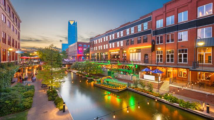 A river near bricked buildings and patios illuminated at night