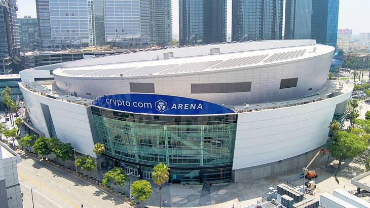 Aerial shot of a round stadium with a sign saying "Crypto.com Arena" near skyscrapers