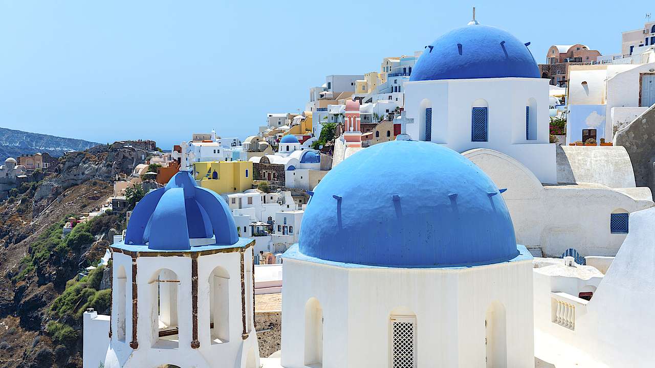 Blue domes with white crosses, on top of white towers, against a blue sky