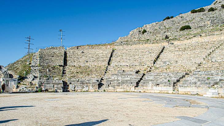 The inside seats and arena of an ancient Greek theatre against a blue sky