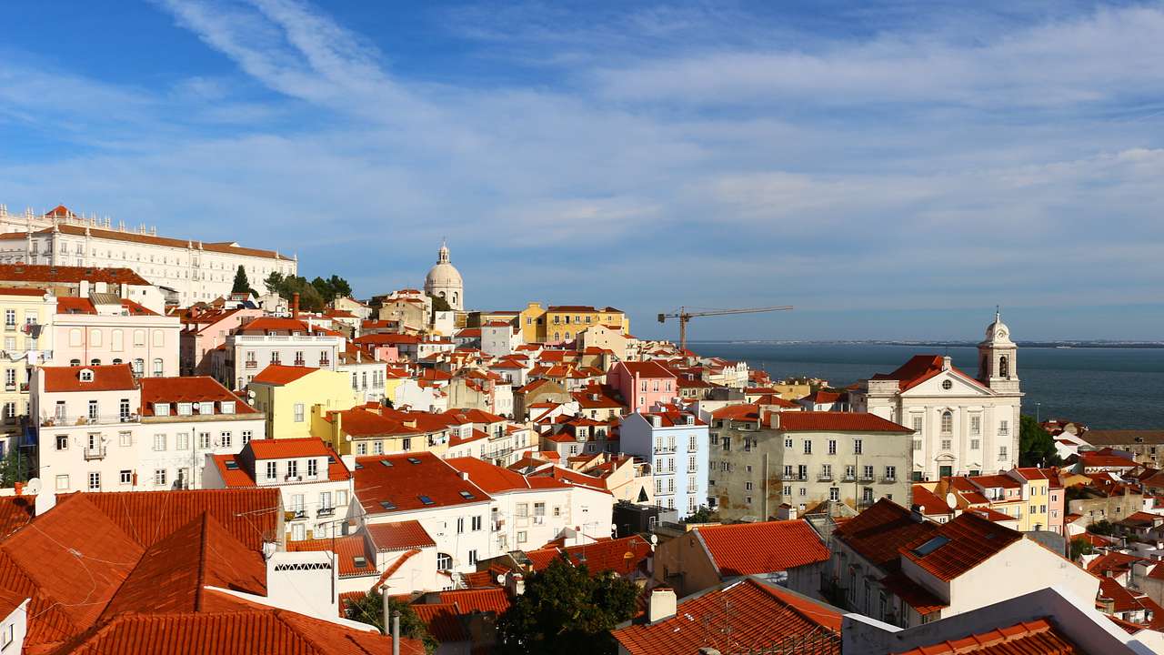 White houses with red rooftops next to the ocean under a blue sky