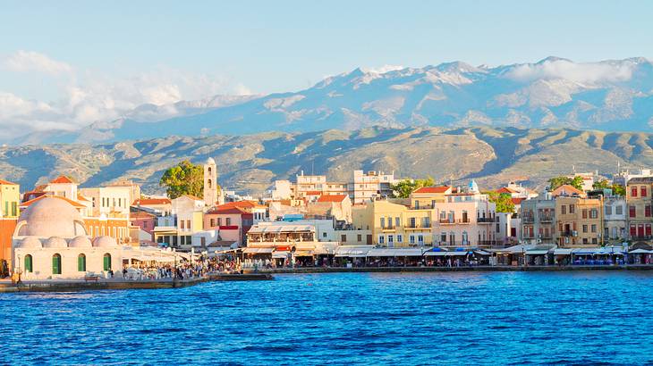 Buildings lined along a body of water, with a mountain range at the back