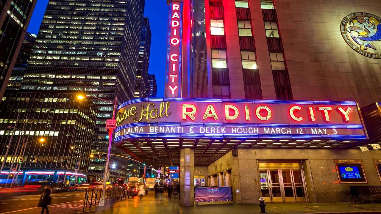 A building on a corner of an intersection with a lit-up sign of "Radio City"