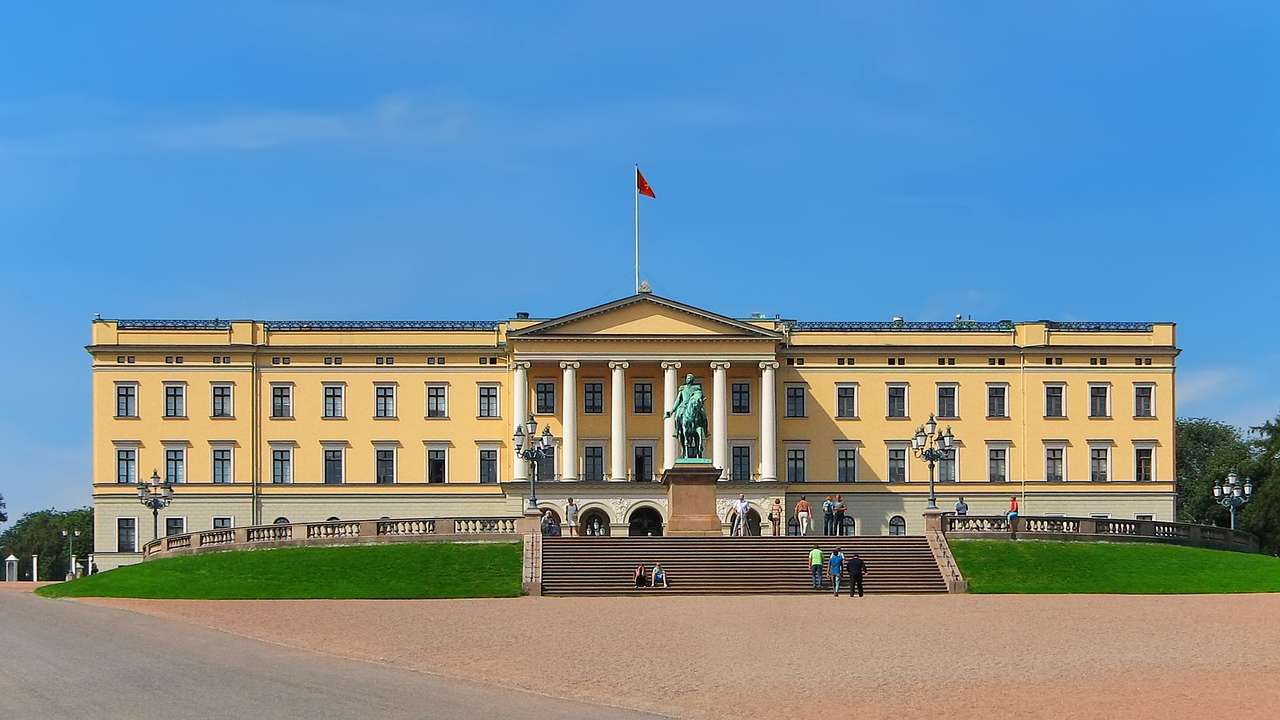 A large yellow palace building with columns and a statue and steps in front of it