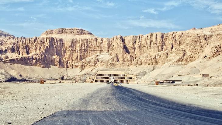 Dirt road leading to an ancient Egyptian temple carved into the mountainside