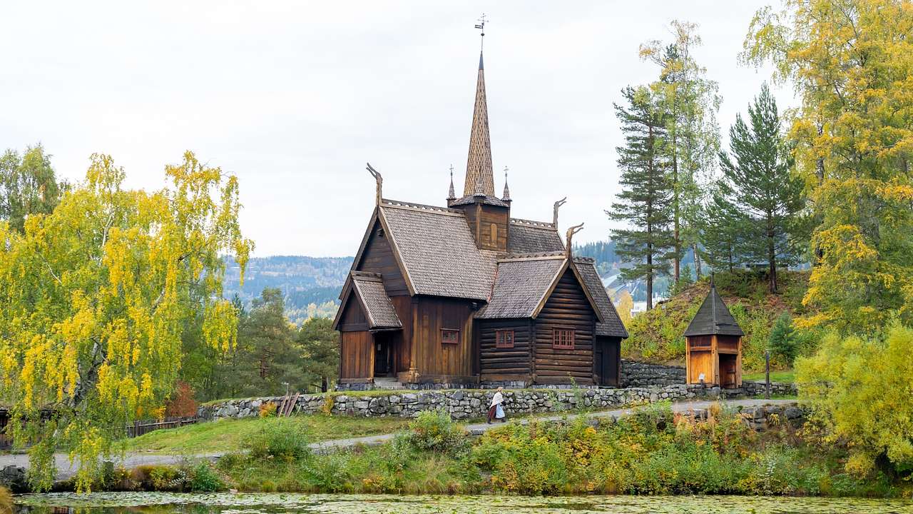 A wooden church building next to trees and a pond with lily pads
