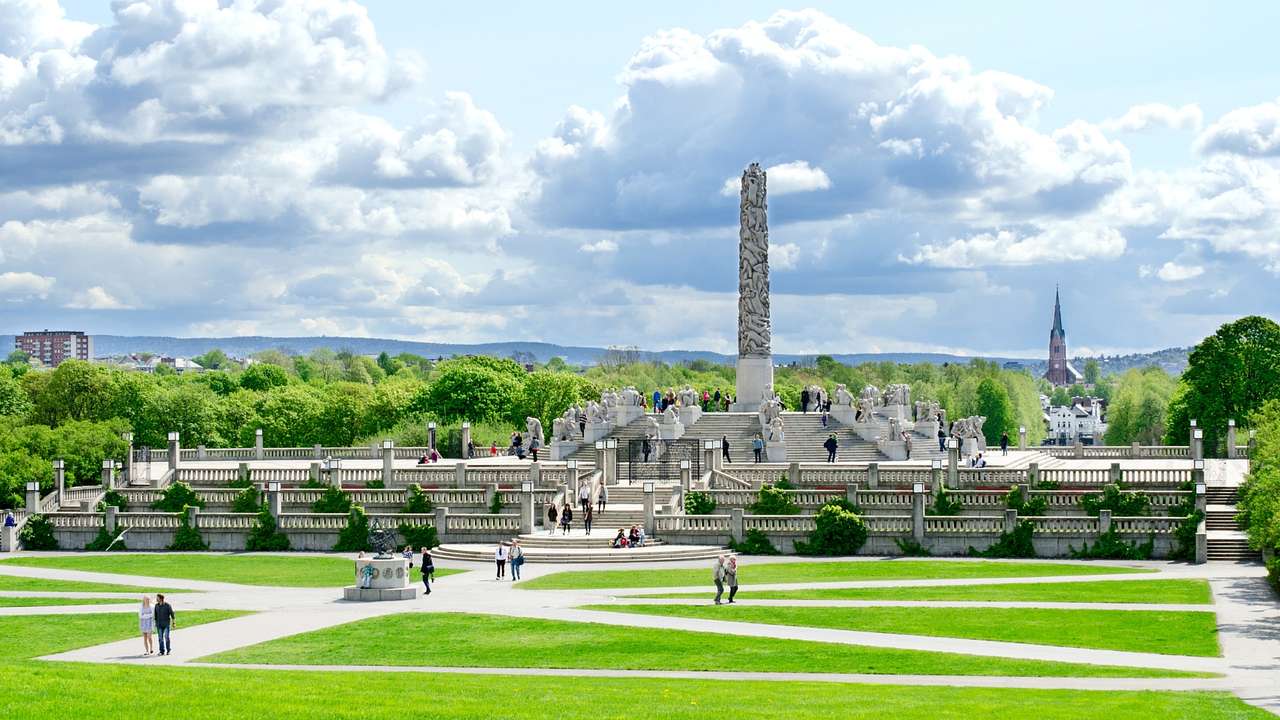 An obelisk monument in a park under a cloudy sky