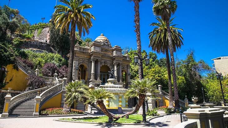 A Neoclassical building and fountain with steps leading to it, next to palm trees