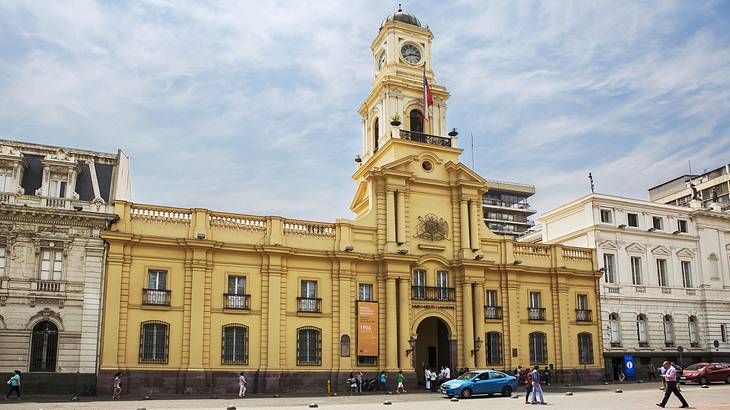 A yellow rectangular building with a tall tower along a street on a nice daypapachec