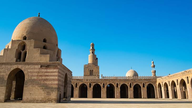 The outside architecture of a mosque from inside its courtyard on a clear blue day