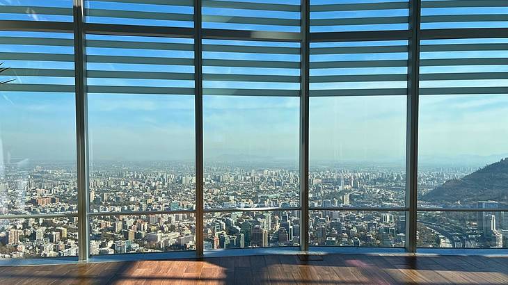 Looking through floor-to-ceiling windows onto a city skyline below on a clear day