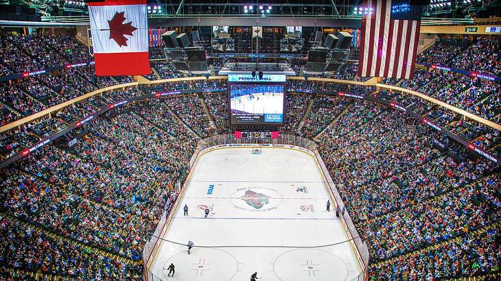 A view of a hockey rink with a game in play and fans surrounding