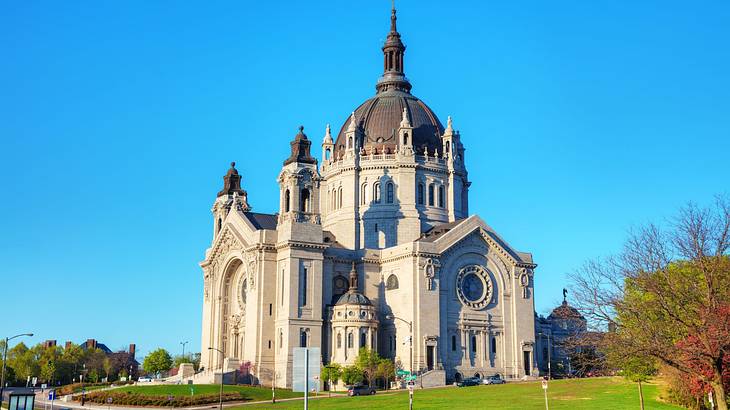 A stone cathedral with a domed roof surrounded by grass under a blue sky