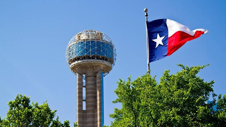 A round observation tower with a Texas flag to the side