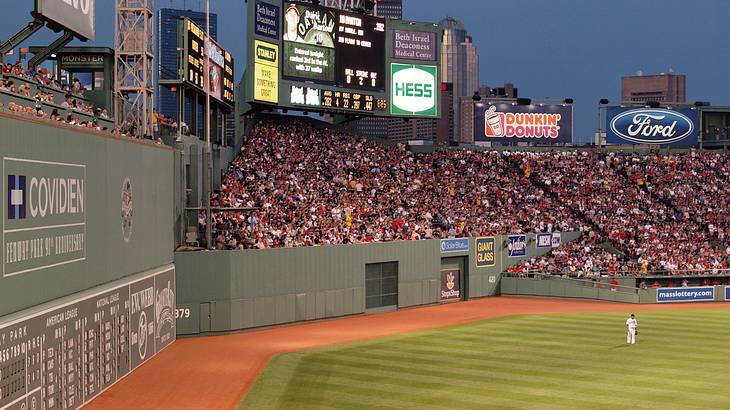 A baseball stadium with fans in the stands and players on the field at night
