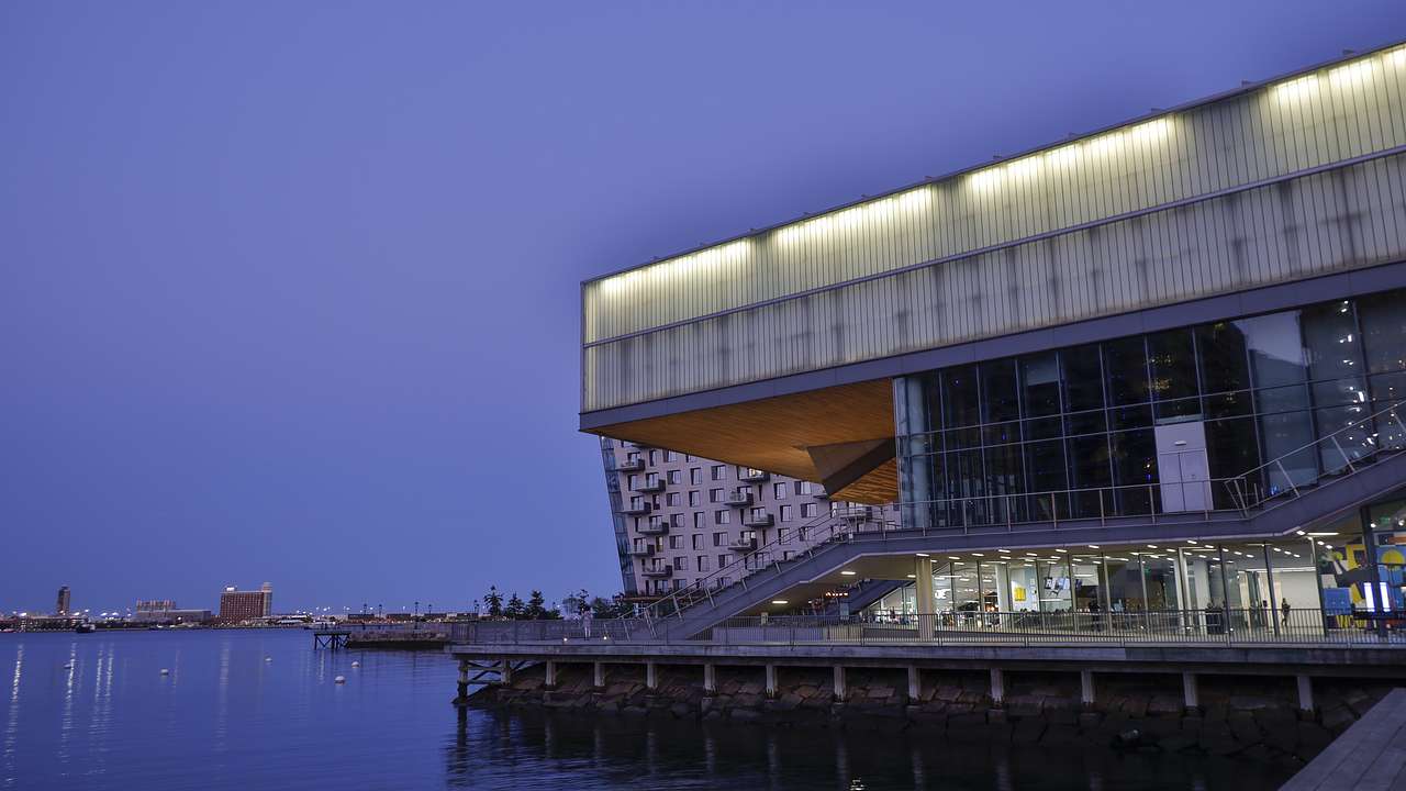 A modern looking museum building with water surrounding it at night
