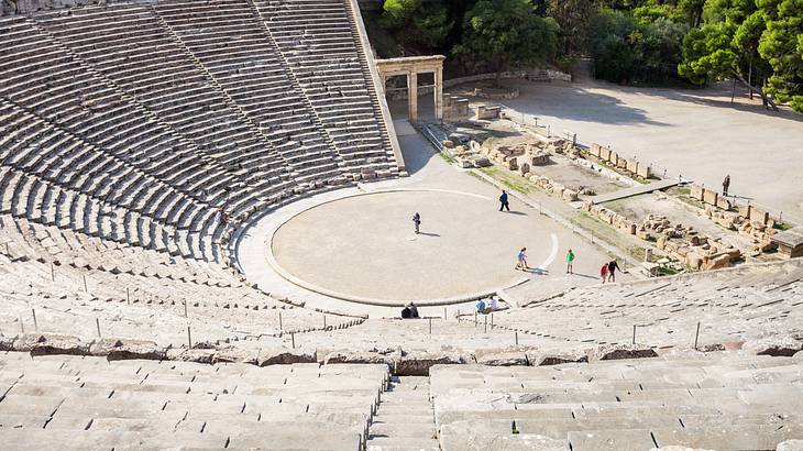 View of an ancient Greek theatre from above with people and ruins below