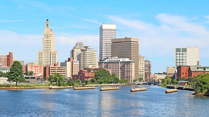 Water next to a city skyline and trees under a clear blue sky