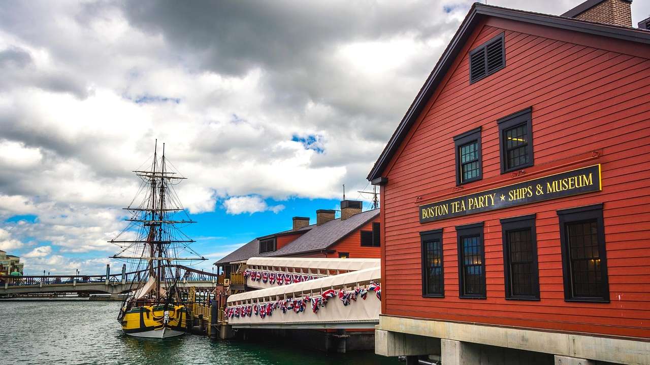 A red building that says "Boston Tea Party & Ships Museum" next to water and a boat