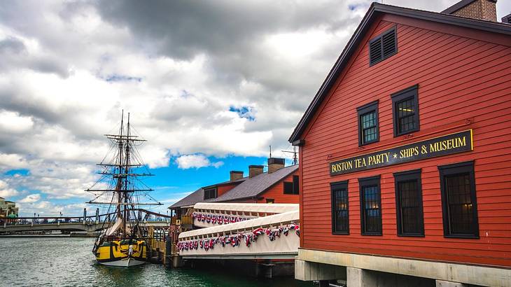 A red building that says "Boston Tea Party & Ships Museum" next to water and a boat