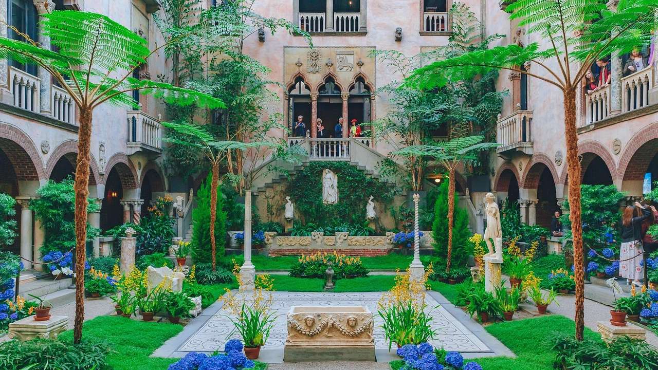 A courtyard with greenery, palm trees, and colorful flowers