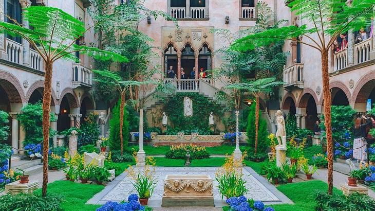 A courtyard with greenery, palm trees, and colorful flowers