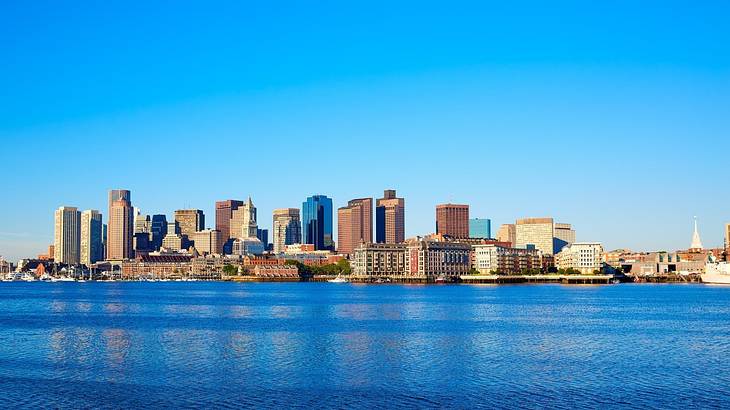 A city skyline with water in front of it under a clear blue sky
