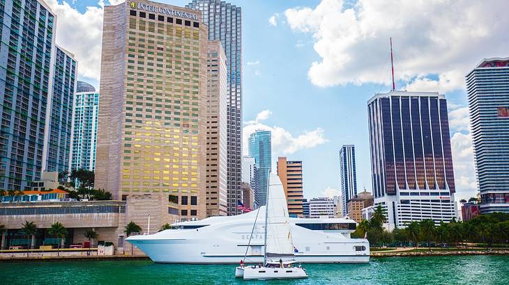 A boat in a marina with skyscrapers behind it